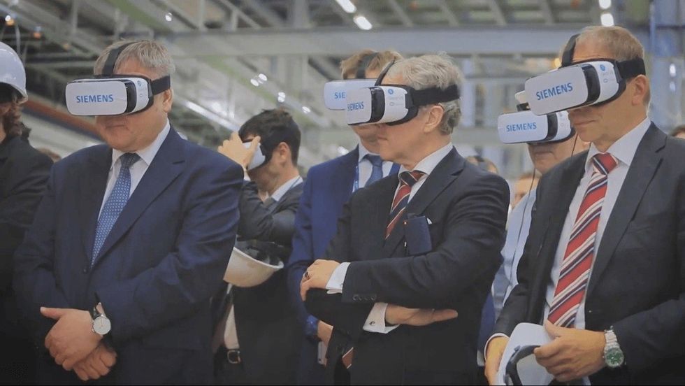 People in suits wearing Siemens VR headsets at an event.