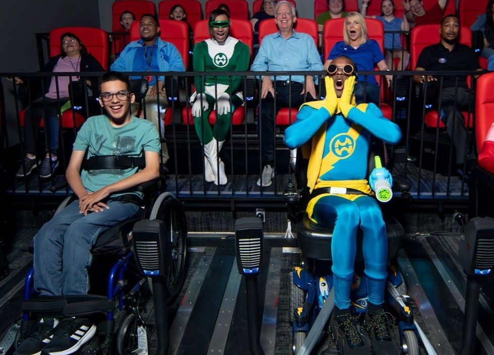 People in wheelchairs enjoy an accessible amusement ride with their families in a theatre setting at Morgan's Wonderland's Ultra-Accessible 4D Magic Cinema
