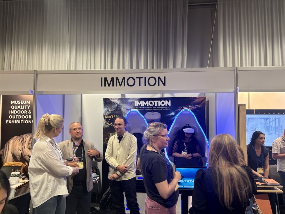 People interacting at the Immotion VR booth, with participants using virtual reality headsets.