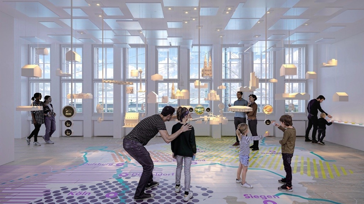 People interacting in a modern, bright room with maps and hanging models.