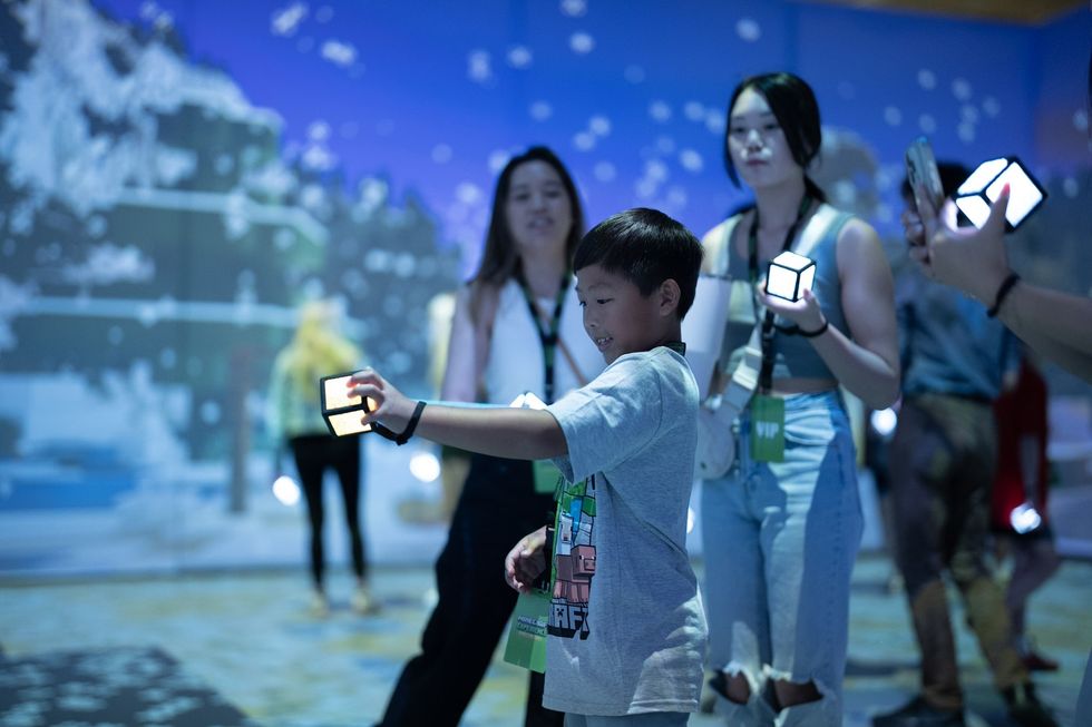 People interacting with glowing cubes in a digital art exhibit.