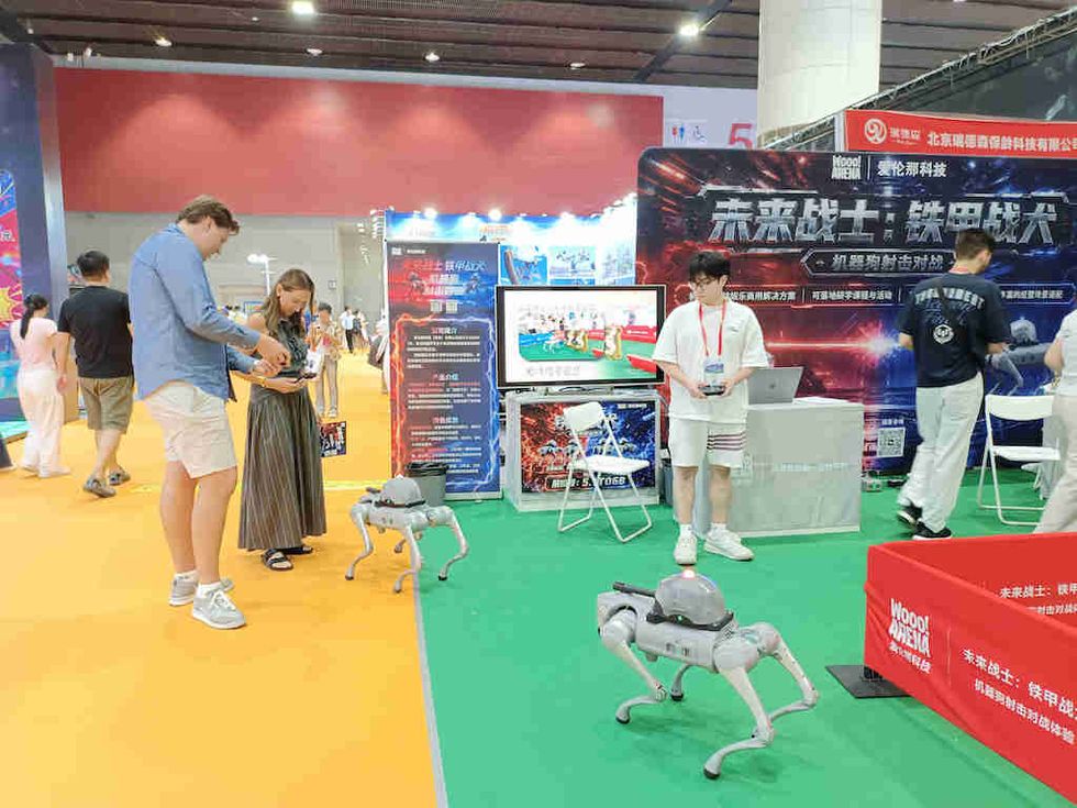 People interacting with robotic dogs at a tech expo booth.