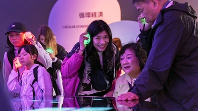 People listening to audio guides with glowing Circulars characters at German Pavilion, Expo 2025 Osaka