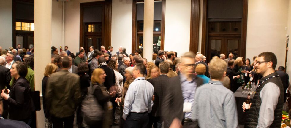 People mingling at a crowded indoor networking event.