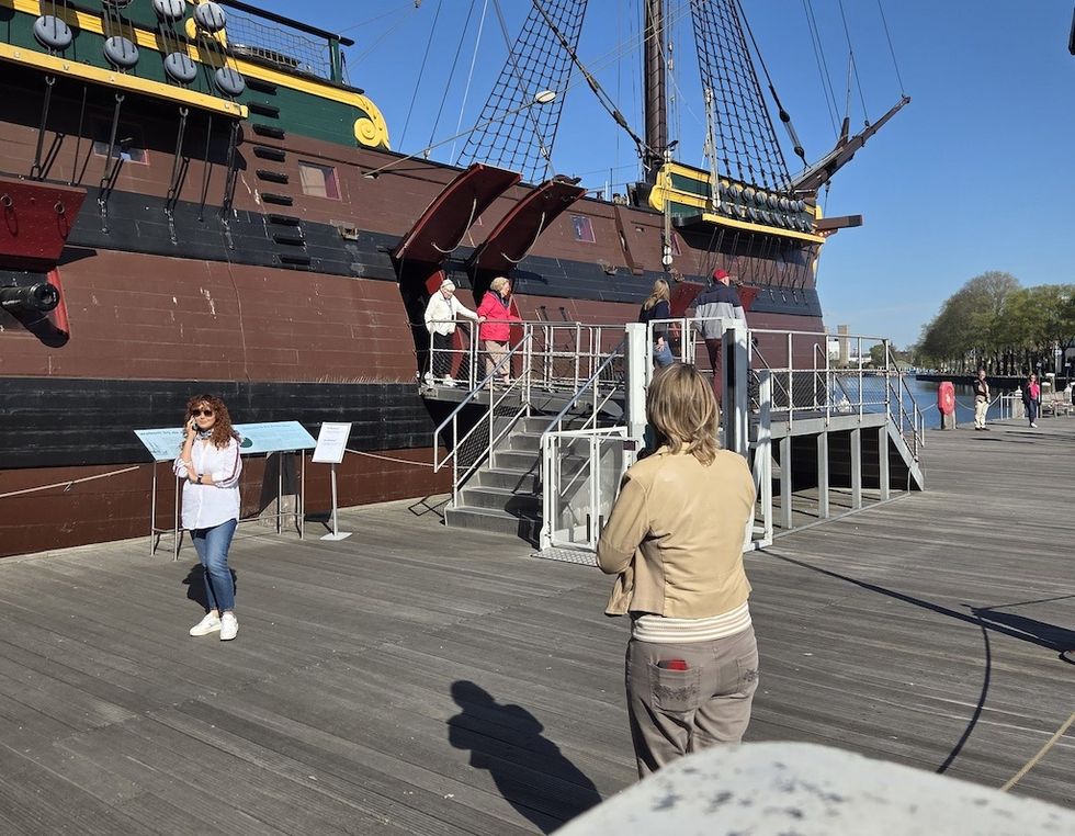 People near a historic ship on display at a dock, listening to audio tour through Podcatcher Pro from Guide-ID