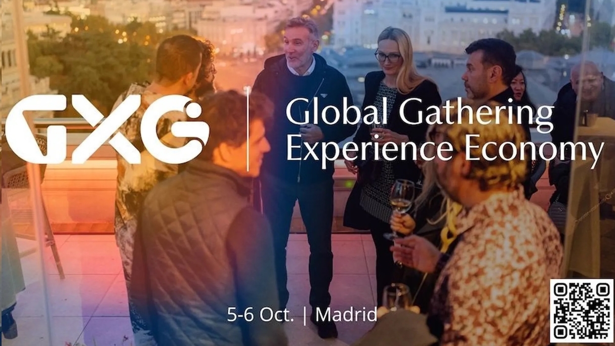 People networking at GXG event in Madrid, overlooking cityscape at sunset.