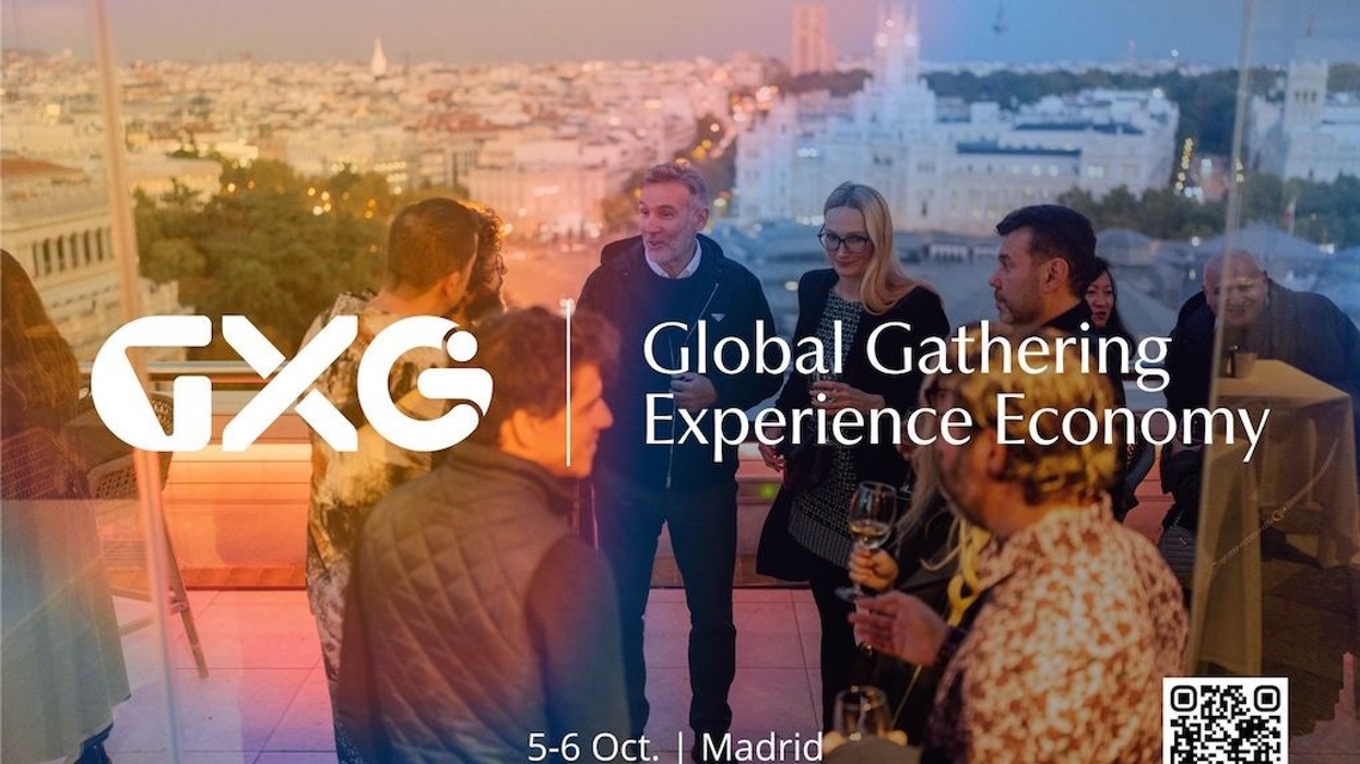 People networking at GXG event in Madrid with cityscape in background.