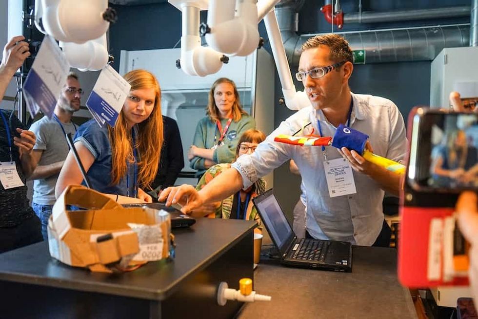 People observe a man demonstrating a colorful object at a presentation, ecsite conference 2023