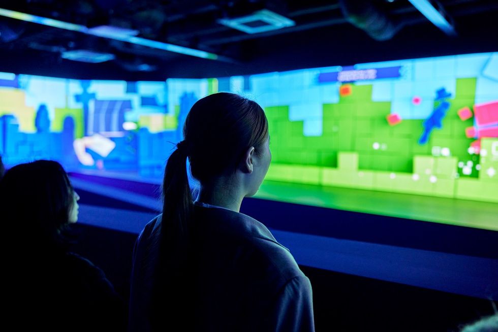 People observing a colorful digital art display on a large screen.