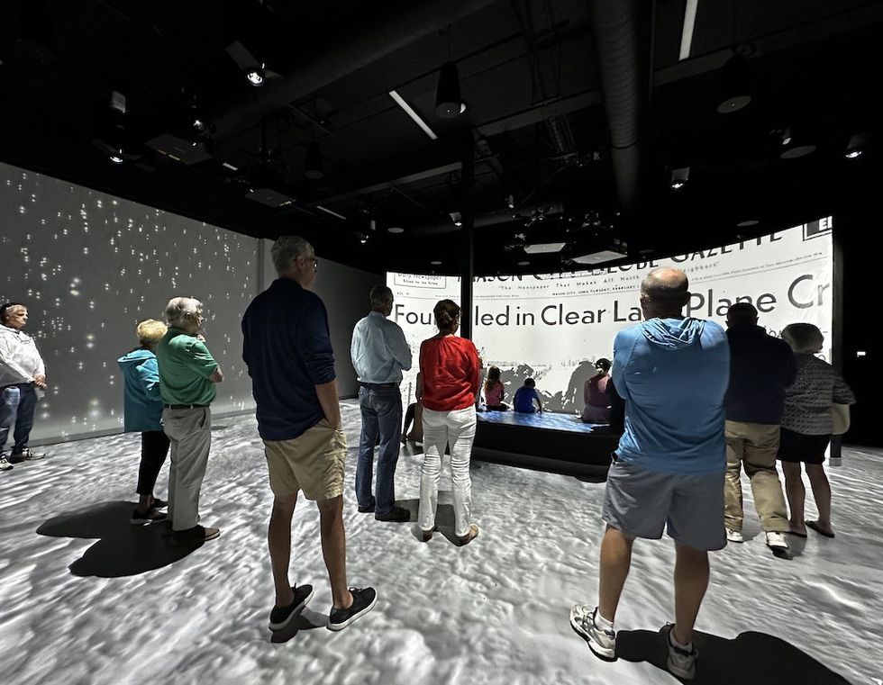 People observing an immersive display with projected text in a dimly lit room.