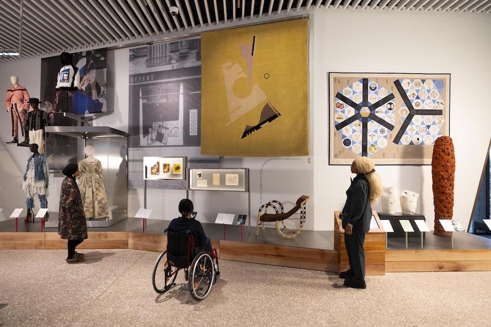People observing art and fashion displays in a museum exhibit at V&A East