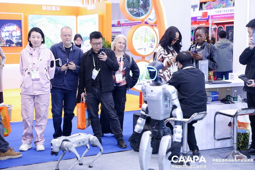 People observing humanoid and robotic dog at a tech exhibition booth.