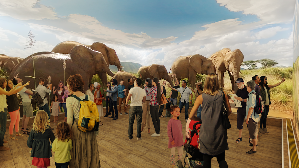 People observing life-sized elephant models in a spacious, indoor exhibit.