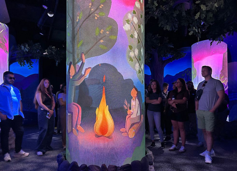 People observing vibrant digital campfire art on columns during the Niagara Takes Flight preshow