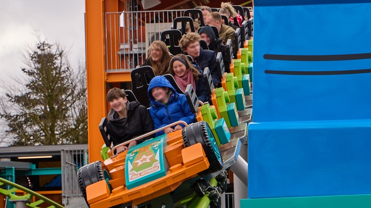 People on a colorful roller coaster ride with excited expressions.