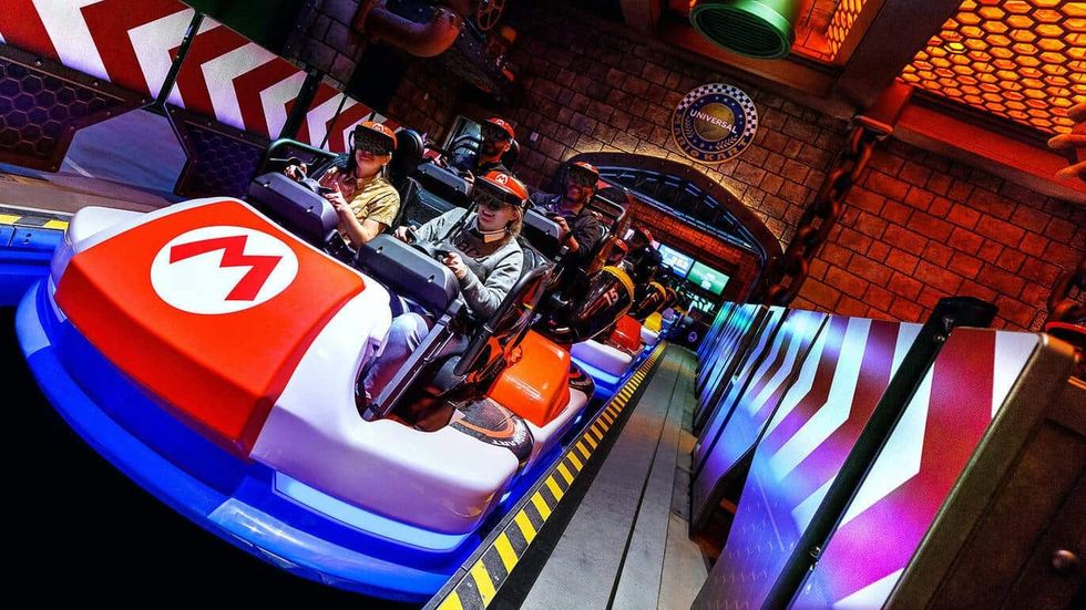 People on a Mario-themed ride, wearing VR headsets, at an amusement park called Universal Studios