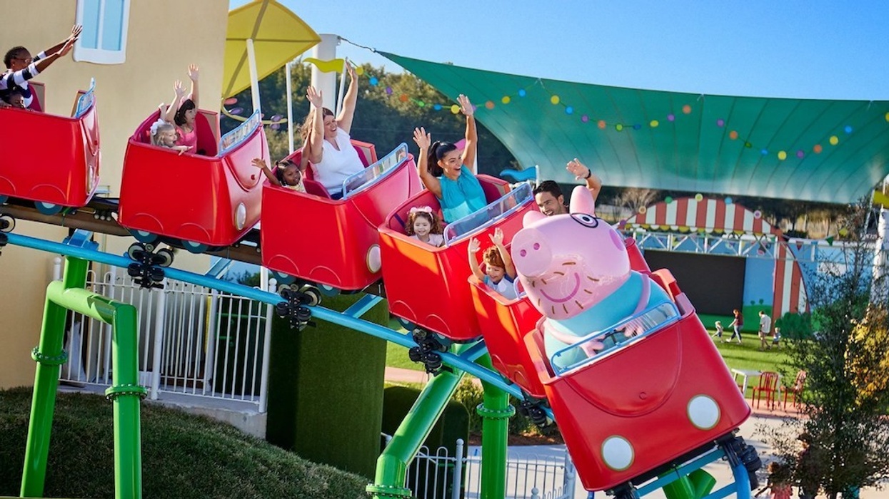 People on a Peppa Pig-themed roller coaster enjoying a ride in an amusement park.