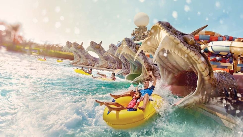 People on a raft enjoy a snake-themed water slide at Yas Waterworld