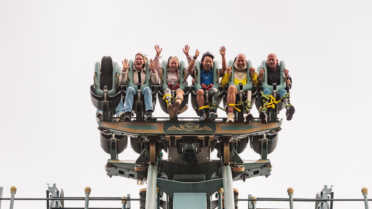 People on a roller coaster, smiling and raising their hands in excitement at Efteling