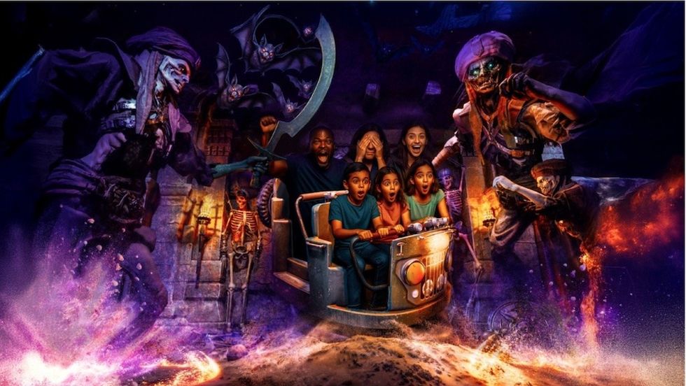 People on a spooky ride encounter skeletons and bats in a thrilling, dark setting.