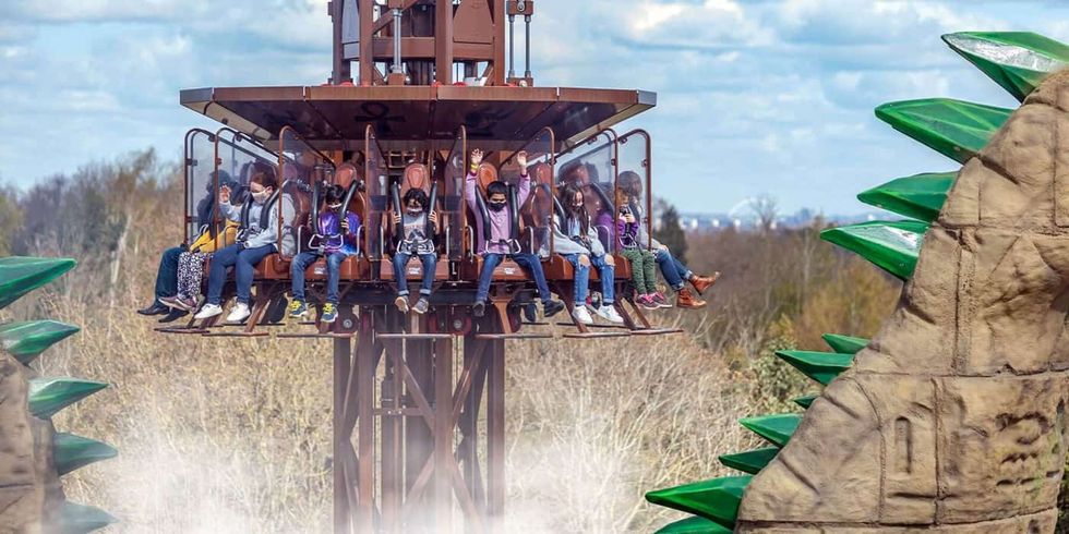 People on an outdoor amusement ride with green dragon-themed decorations.