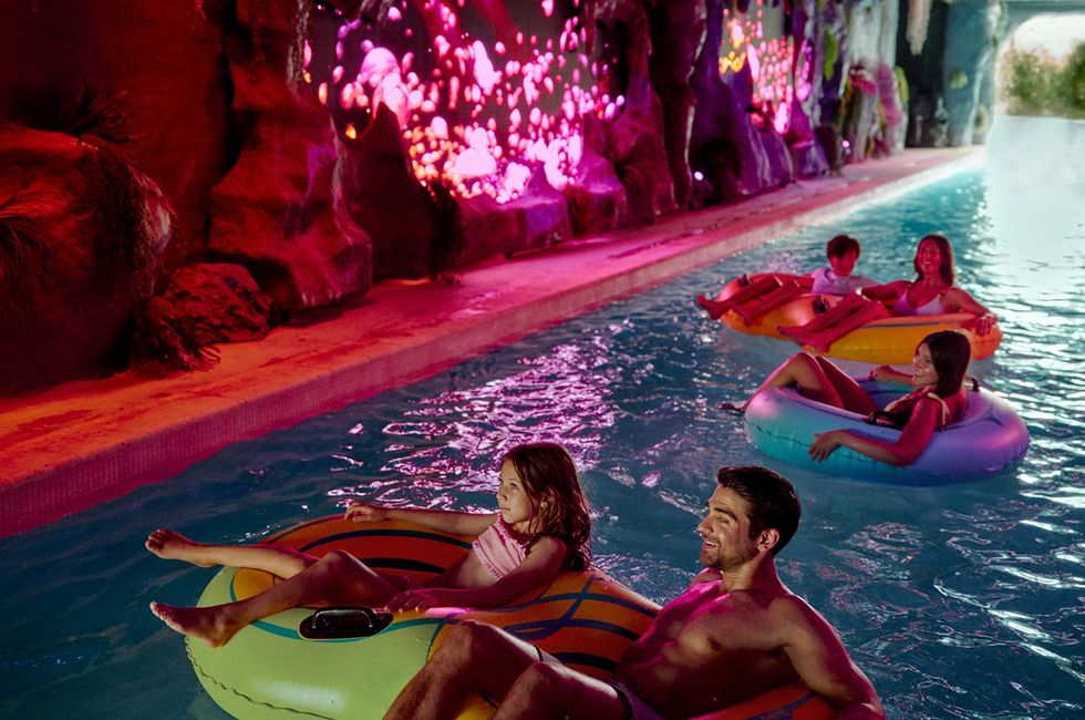 People on inflatable tubes floating in a cave pool at Great Tides Waterpark with colorful light effects