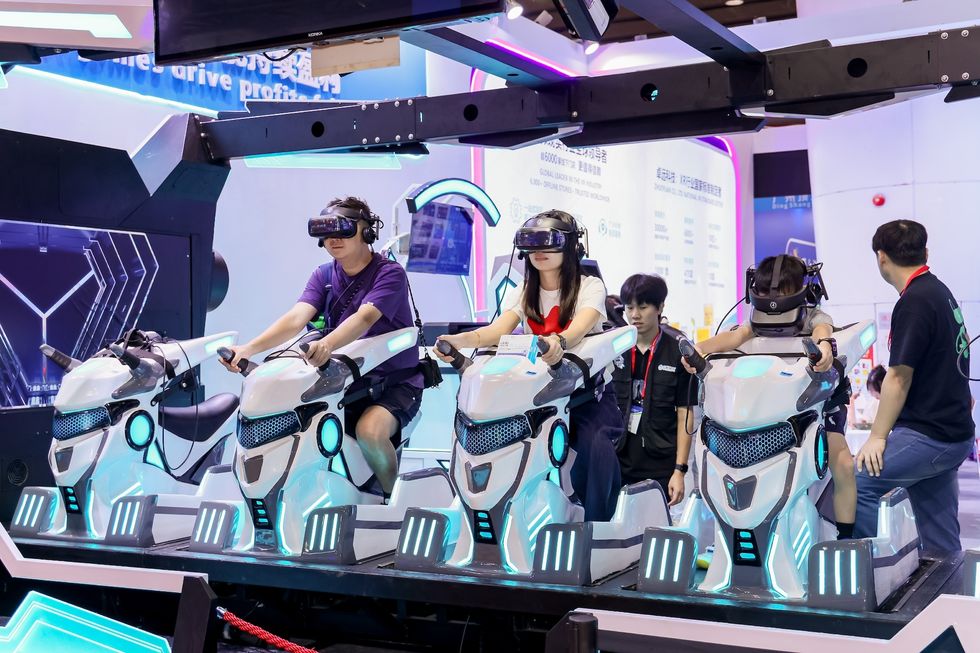 People on VR motorbikes at a tech expo exhibit.