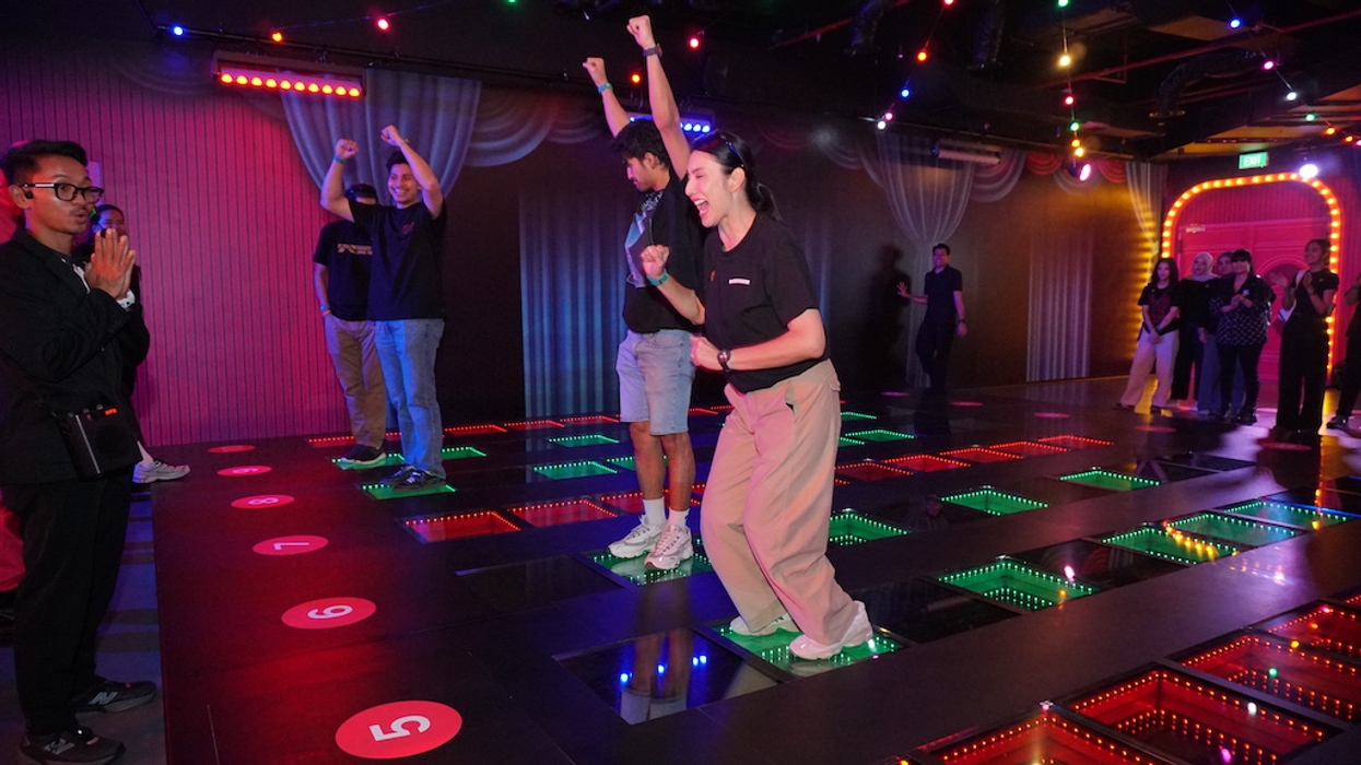 People playing a light-up floor game, celebrating with cheers and raised arms.