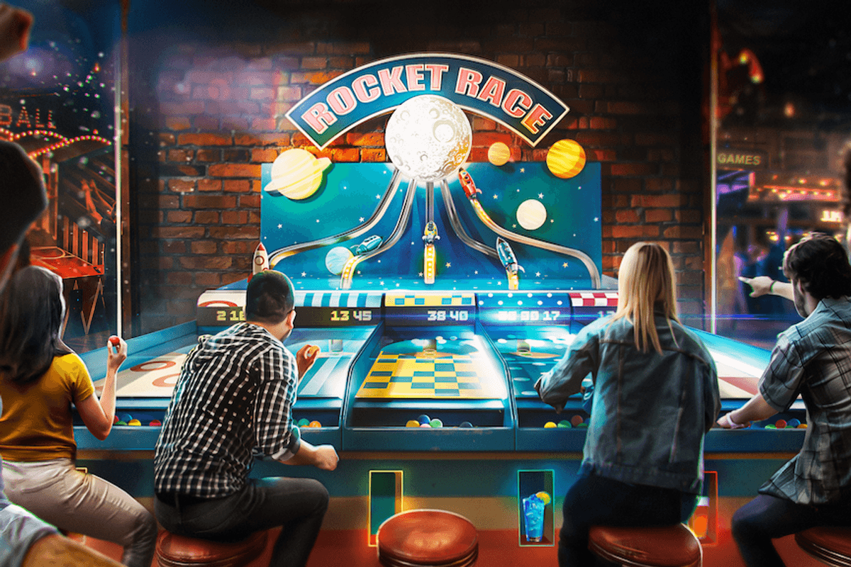 People playing an arcade game called "Rocket Race" with colorful lights and cheering.