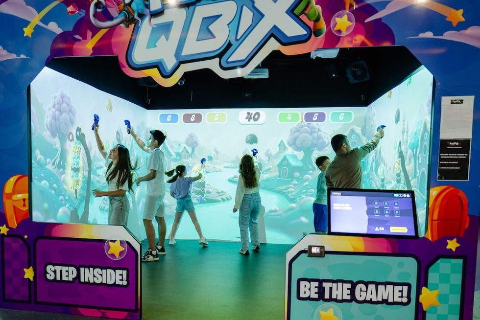 People playing an interactive wall game at a vibrant arcade attraction, QBIX Play
