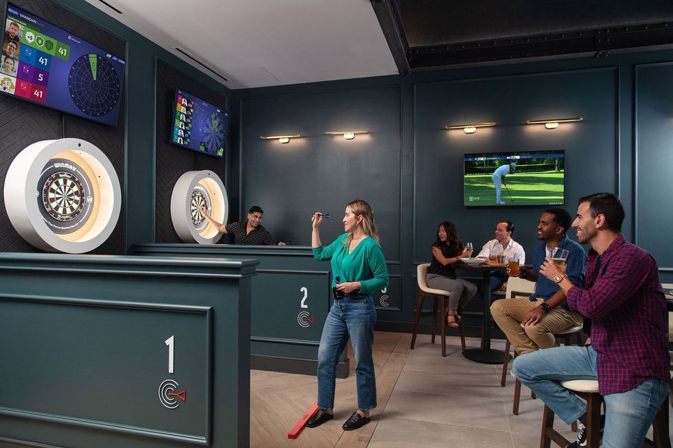 People playing Dartsee interactive darts in a lounge with TV screens.