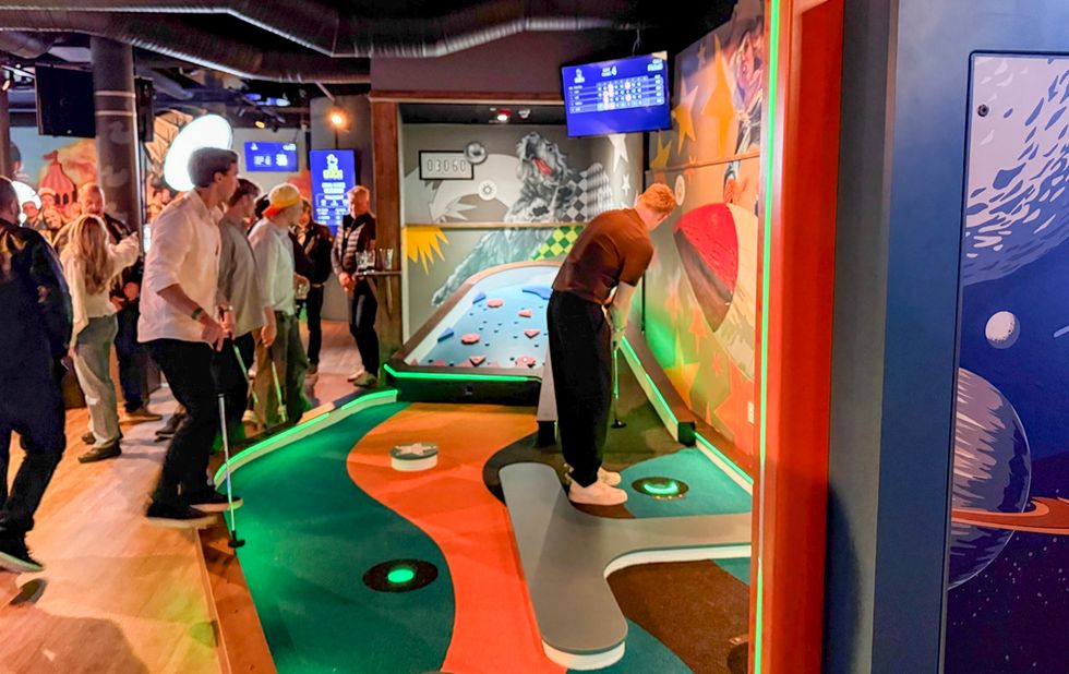 People playing mini golf from 360Golf indoors with colourful, space-themed decor.