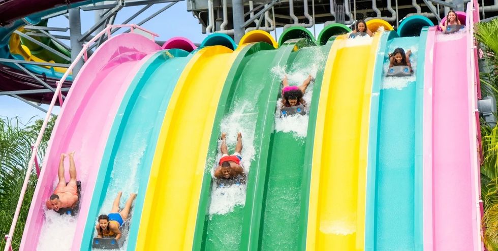 People racing down colorful water slides in an amusement park.