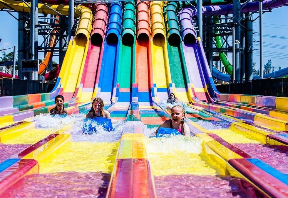 People racing down colorful water slides on blue mats at Raging Waters in Sydney