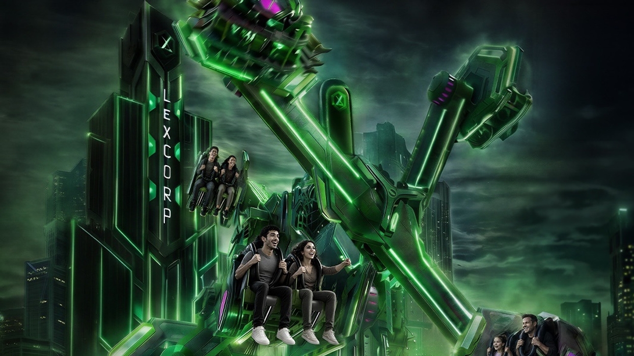 People riding a futuristic green themed amusement park ride at Warner Bros. World Abu Dhabi at night.