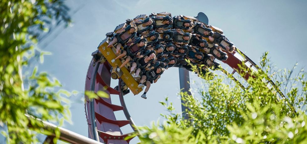 People riding a roller coaster upside down on a loop under a clear blue sky.