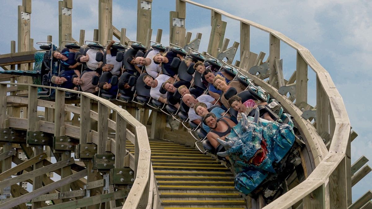 People riding a wooden roller coaster with a blue dragon-themed front.