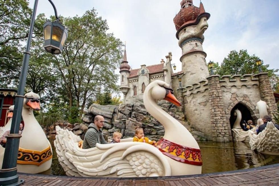 People riding swan boats near a fairy tale castle at Efteling
