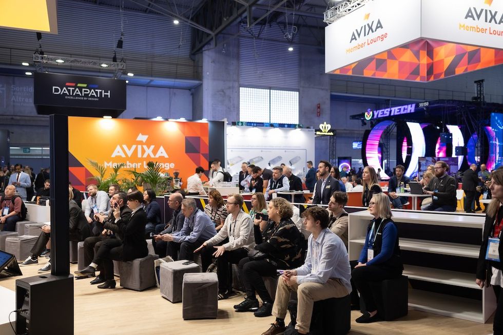 People seated at AVIXA Member Lounge during a tech conference.