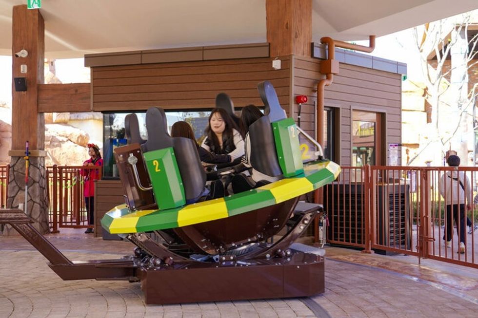 People seated on a circular amusement ride Dancing Mauris at Lotte World Busan theme park.