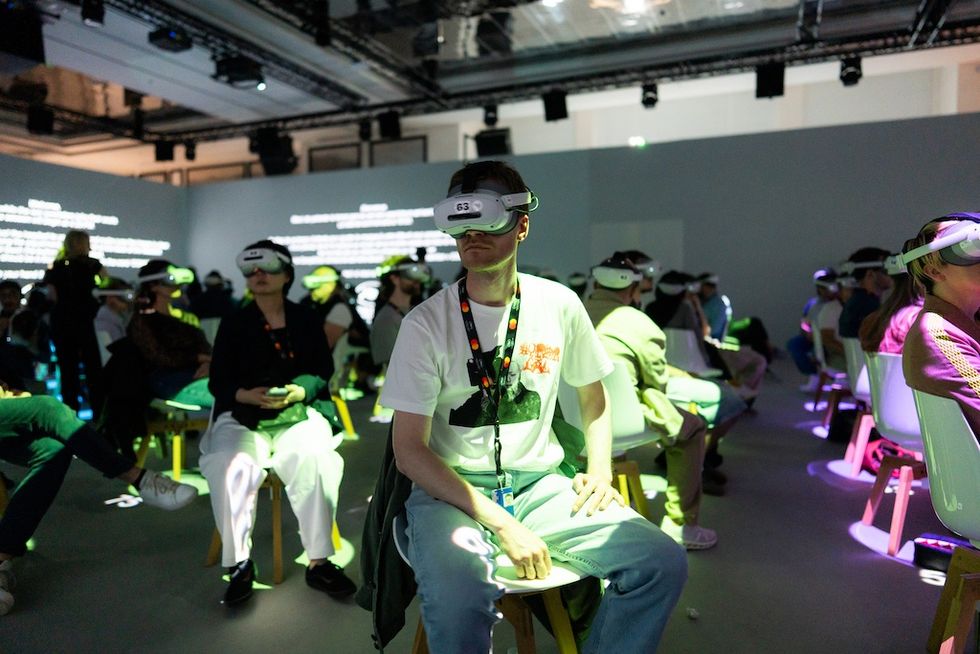 People seated wearing VR headsets at an event in a dimly lit room.