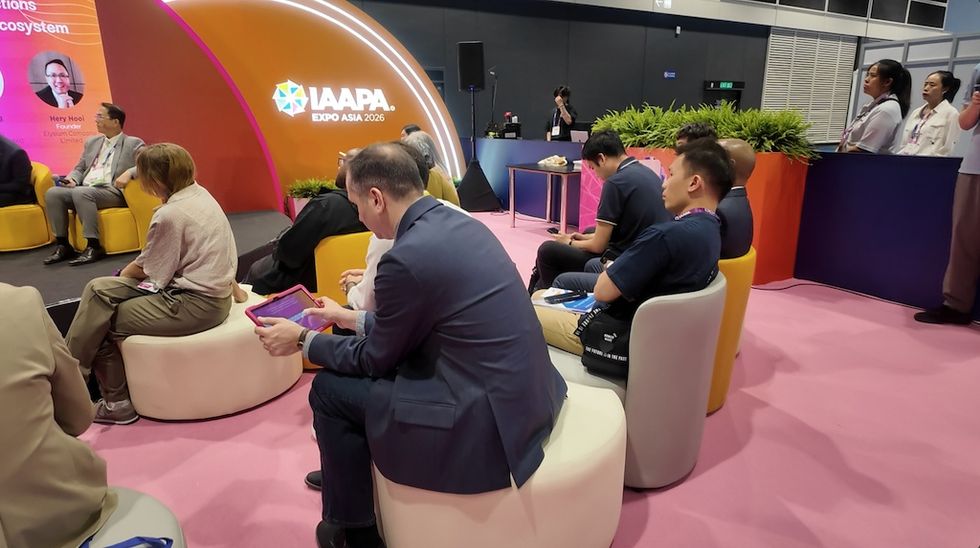 People sitting and listening at the IAAPA Expo Asia 2026 event, with a colorful backdrop.