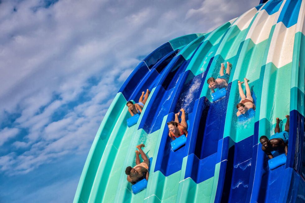 People sliding down colorful water slides under a blue sky at Island H2O Water Park