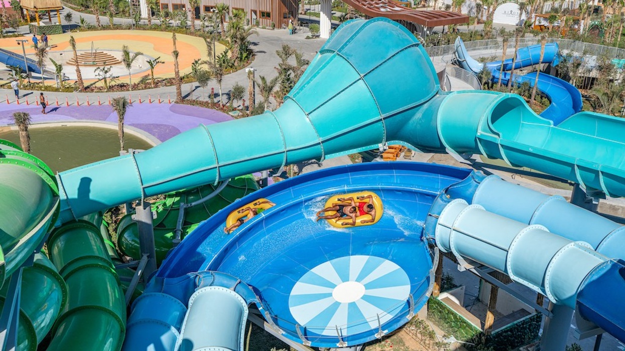 People sliding on a spiraling water slide at a colorful water park.