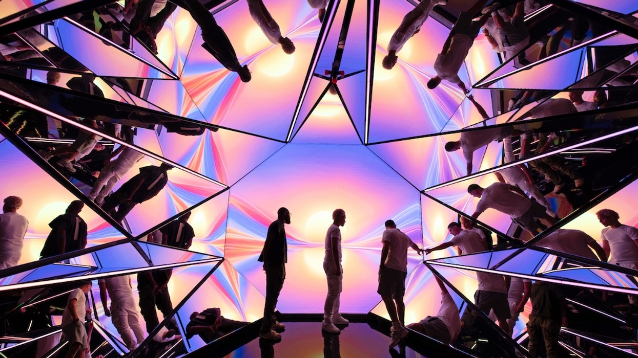 People stand in a mirrored room with colorful, distorted light reflections - kaleidoscope immersive experience Edge NYC