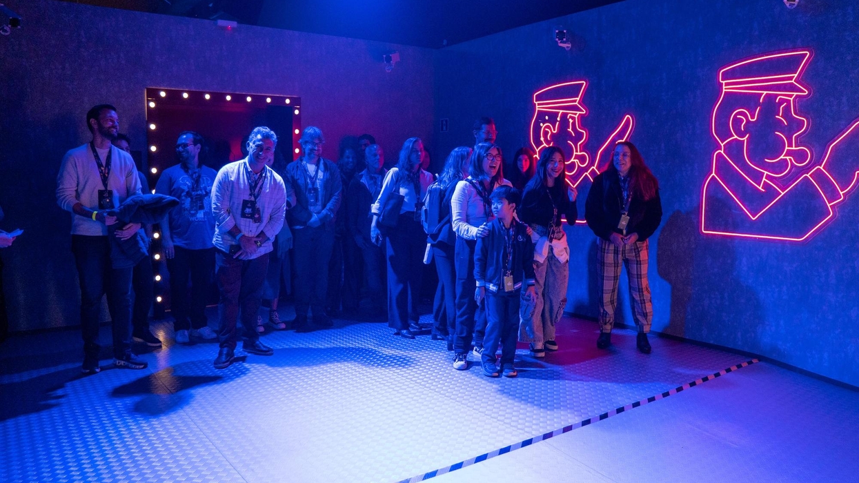 People stand under blue lights with neon illustrations on the wall