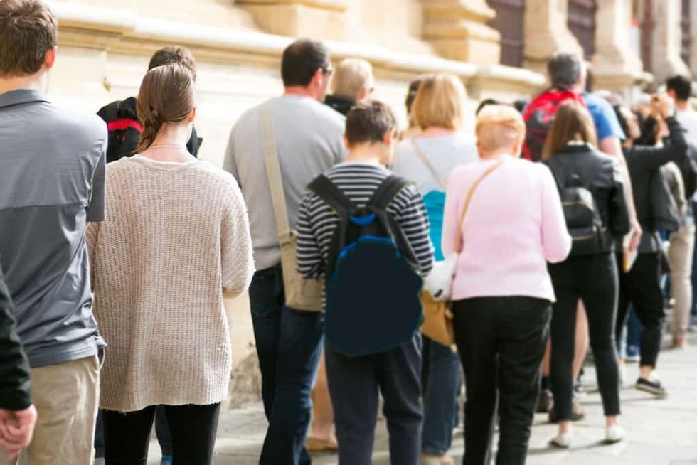 People standing in a long line outdoors, wearing casual clothing.