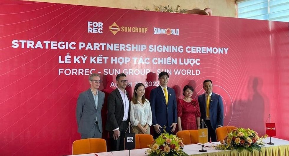 people standing in front of red banner at FORREC and Sun Group signing ceremony