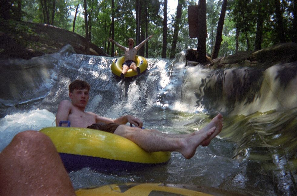 People tubing down a water slide in a forested area at the now closed Action Park, Vernon