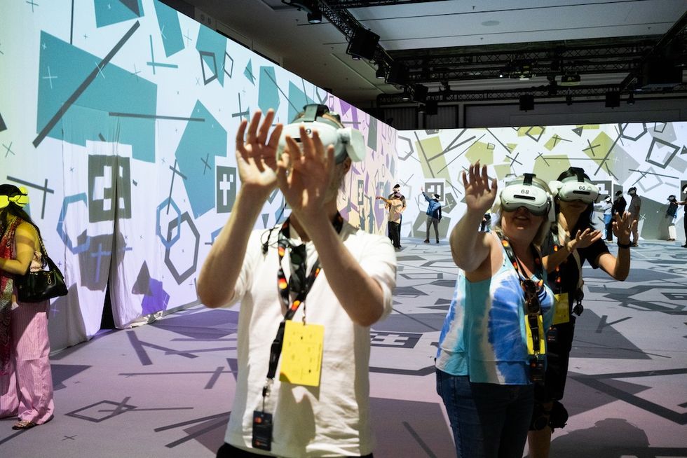People using VR headsets in a room with geometric patterned walls.